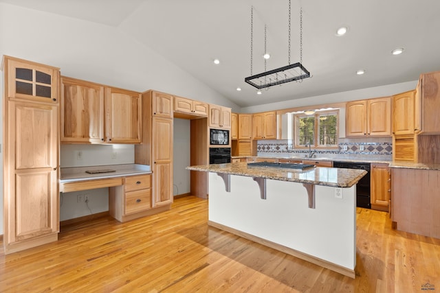 kitchen with light stone counters, a kitchen island, black appliances, and light wood-type flooring