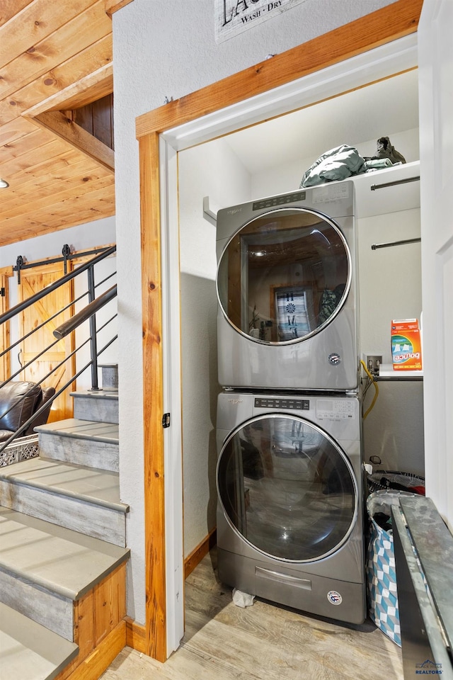 clothes washing area with light wood-type flooring and stacked washer and dryer