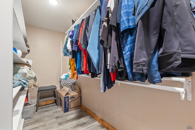 walk in closet with light hardwood / wood-style flooring