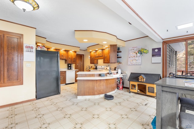 kitchen featuring kitchen peninsula, white dishwasher, black fridge, and a breakfast bar area