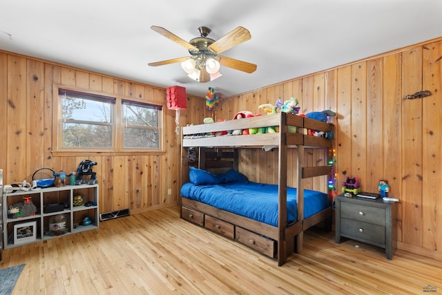 bedroom with light hardwood / wood-style flooring and wood walls