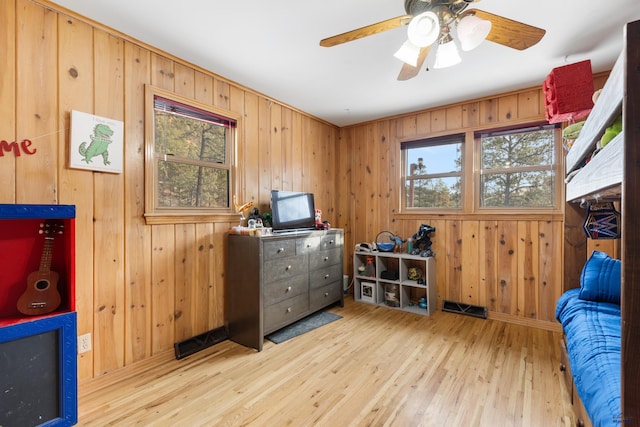 miscellaneous room featuring light wood-type flooring, wooden walls, and a healthy amount of sunlight