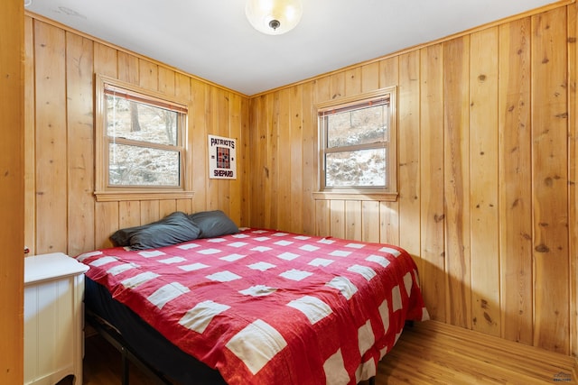 bedroom featuring wood-type flooring, multiple windows, and wooden walls