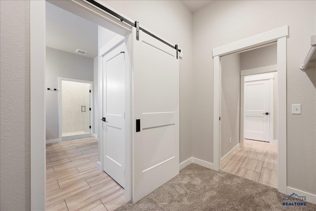 corridor featuring a barn door and light carpet