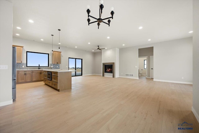 kitchen with a center island, tasteful backsplash, pendant lighting, a fireplace, and light wood-type flooring