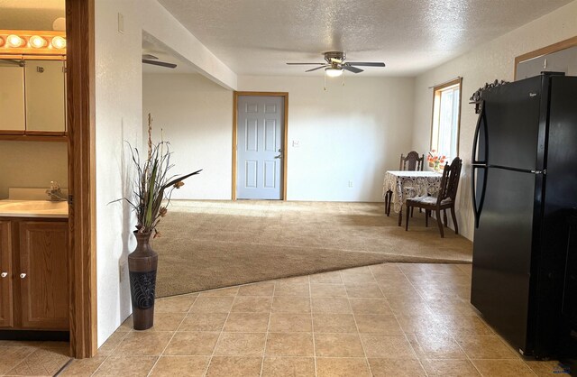 kitchen with ceiling fan, sink, light colored carpet, a textured ceiling, and black refrigerator