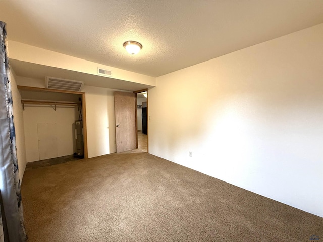 unfurnished bedroom featuring carpet flooring, electric water heater, a textured ceiling, and a closet