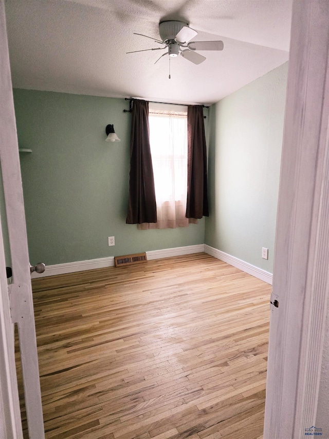 unfurnished room featuring a textured ceiling, ceiling fan, and light hardwood / wood-style flooring