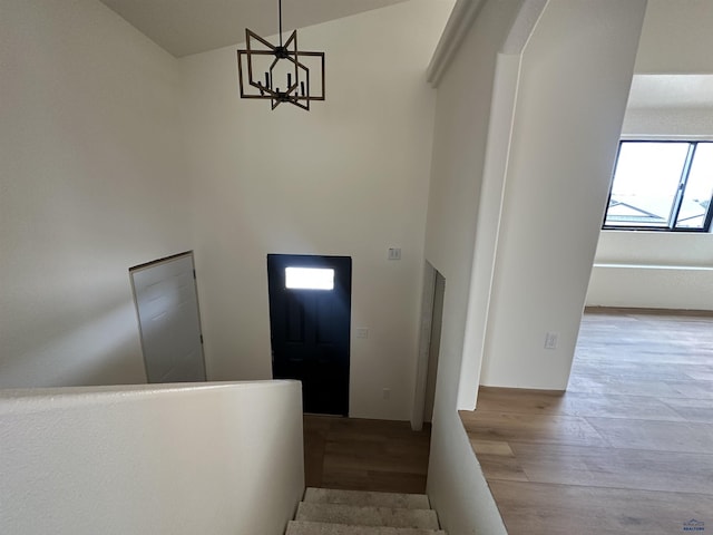 foyer featuring a high ceiling, wood finished floors, a skylight, and an inviting chandelier