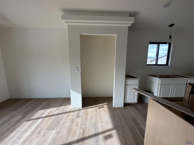 interior space featuring white cabinets, hanging light fixtures, and wood finished floors