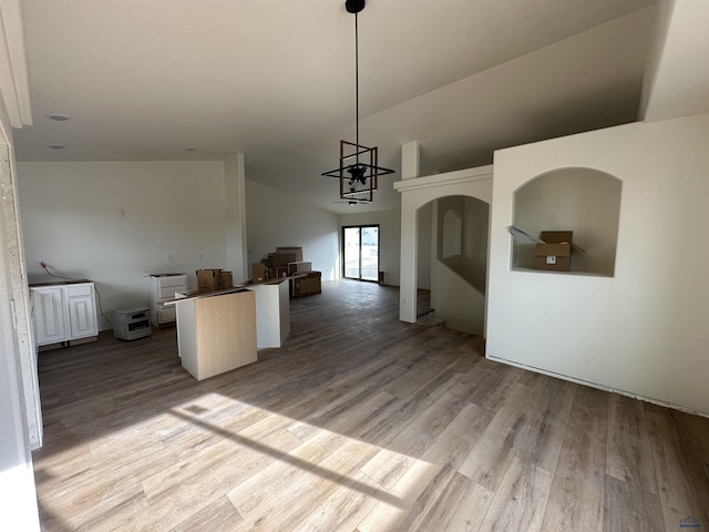 kitchen with pendant lighting, wood finished floors, vaulted ceiling, and open floor plan