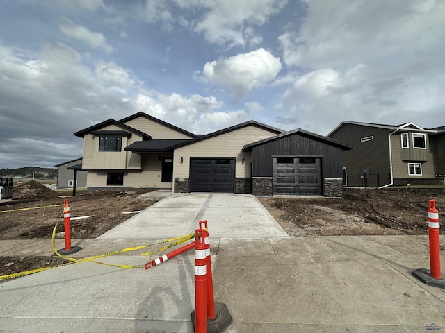 view of front of property featuring stone siding, concrete driveway, and a garage