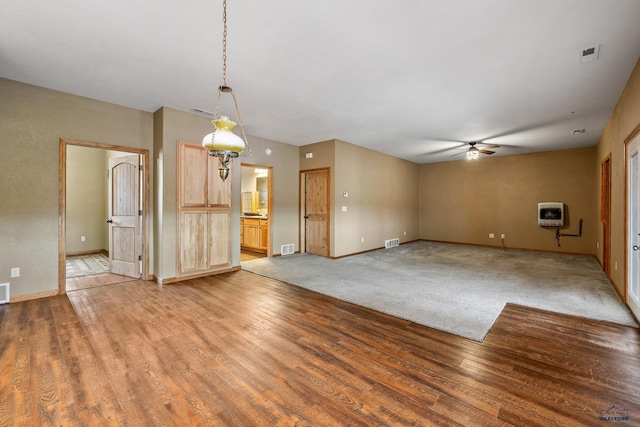 unfurnished living room with light wood-type flooring, heating unit, and ceiling fan