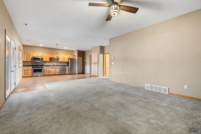 unfurnished living room featuring light colored carpet, ceiling fan, and sink