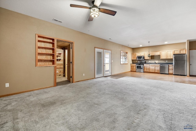 unfurnished living room with ceiling fan and light carpet