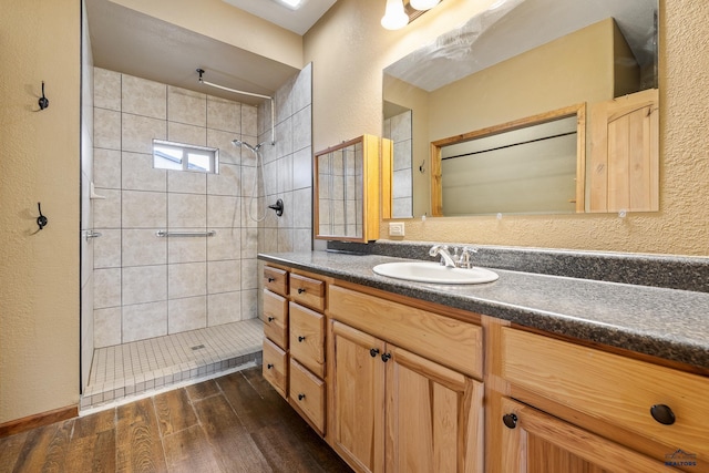 bathroom featuring vanity, wood-type flooring, and tiled shower