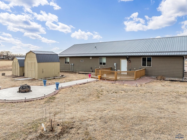 rear view of property featuring a storage unit, an outdoor fire pit, and a wooden deck