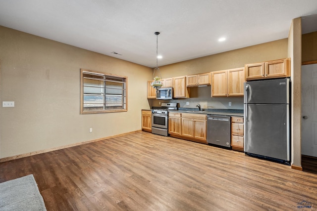 kitchen featuring sink, light wood-type flooring, light brown cabinetry, appliances with stainless steel finishes, and decorative light fixtures