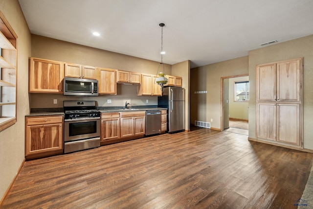 kitchen with light brown cabinets, dark wood-type flooring, sink, hanging light fixtures, and stainless steel appliances