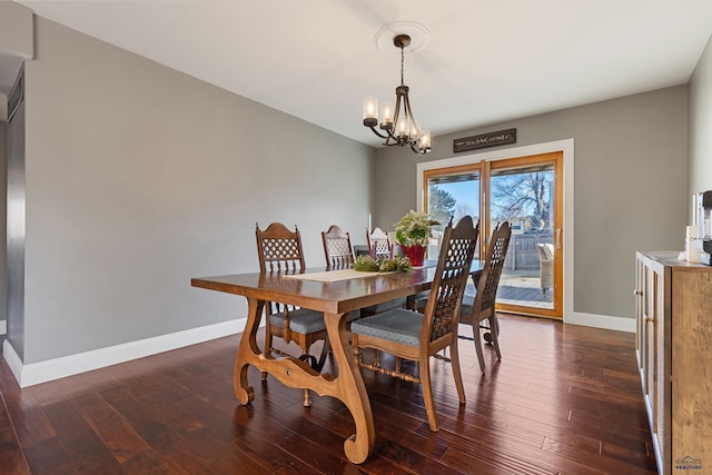 dining area with dark hardwood / wood-style floors and an inviting chandelier