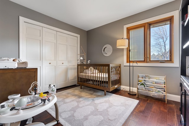 bedroom featuring dark hardwood / wood-style floors, a crib, and a closet