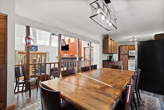 dining space featuring ceiling fan with notable chandelier and dark hardwood / wood-style floors