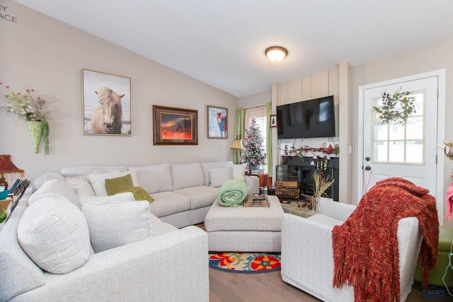 living room with a large fireplace, wood-type flooring, and lofted ceiling