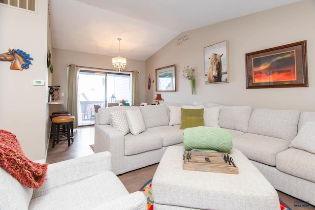 living room with vaulted ceiling, wood-type flooring, and an inviting chandelier