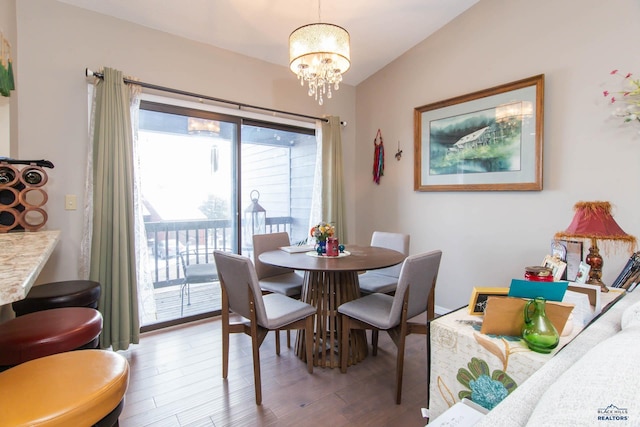 dining area with hardwood / wood-style floors, vaulted ceiling, and a notable chandelier