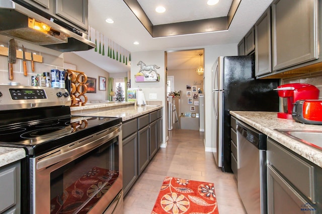 kitchen featuring light stone countertops, tasteful backsplash, gray cabinetry, stainless steel appliances, and sink