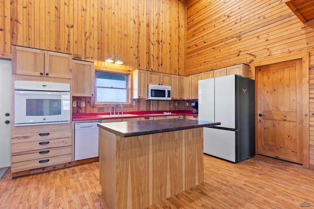 kitchen featuring a center island, a high ceiling, light hardwood / wood-style flooring, white appliances, and light brown cabinetry