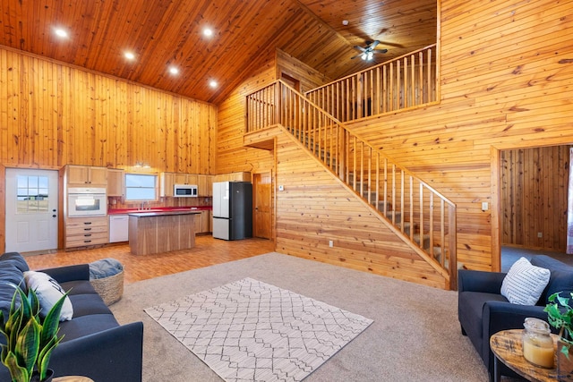 carpeted living room featuring high vaulted ceiling, ceiling fan, wooden ceiling, and sink