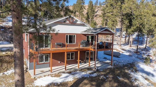 snow covered house featuring central air condition unit and a wooden deck