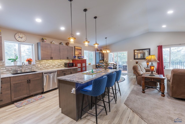 kitchen featuring backsplash, stainless steel dishwasher, a breakfast bar, sink, and a center island