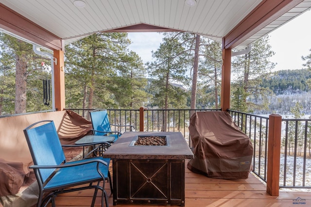 wooden deck featuring a fire pit and a grill