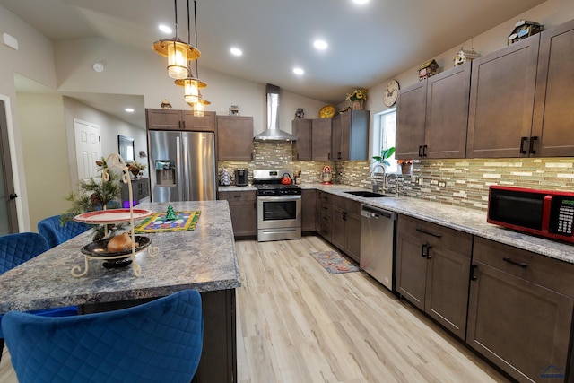 kitchen with stainless steel appliances, wall chimney range hood, pendant lighting, a center island, and lofted ceiling