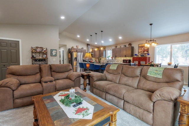 living room with a notable chandelier, light carpet, and vaulted ceiling