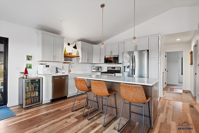 kitchen with sink, beverage cooler, stainless steel appliances, pendant lighting, and light hardwood / wood-style floors