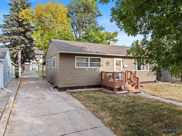 bungalow-style house featuring a front lawn and an outdoor structure