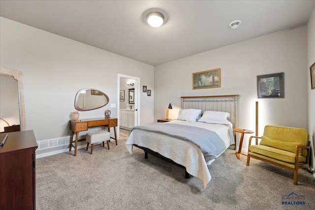 bedroom featuring ensuite bathroom and light carpet