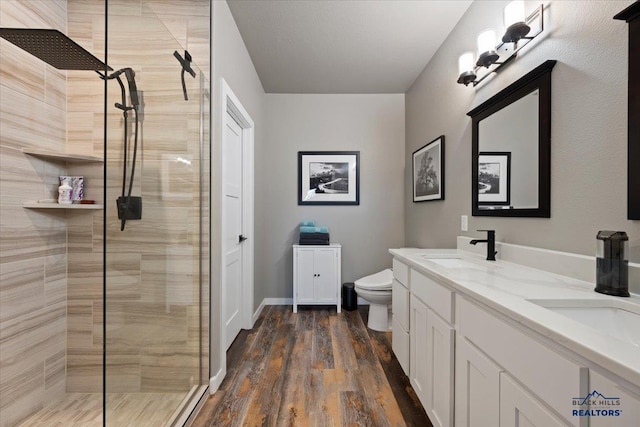 bathroom featuring a tile shower, vanity, hardwood / wood-style flooring, and toilet