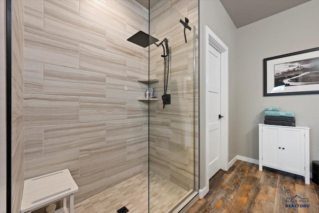 bathroom with a tile shower and hardwood / wood-style flooring