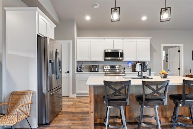 kitchen featuring white cabinets, appliances with stainless steel finishes, decorative light fixtures, and sink