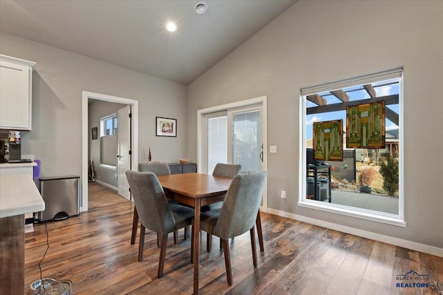 dining space featuring dark wood-type flooring and high vaulted ceiling