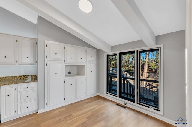 interior space with vaulted ceiling with beams and light hardwood / wood-style floors