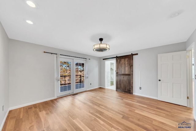 spare room with a barn door and light hardwood / wood-style flooring