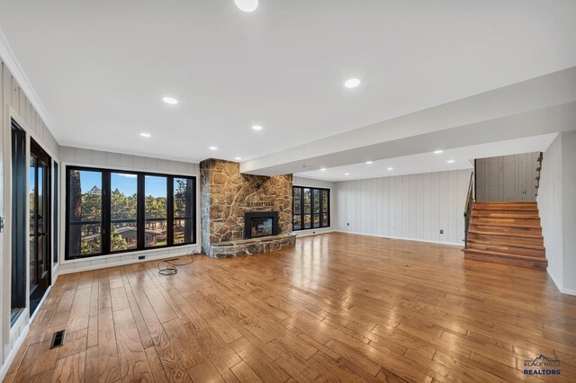 unfurnished living room with a stone fireplace and light hardwood / wood-style flooring