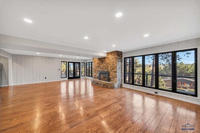 unfurnished living room with light hardwood / wood-style floors and a stone fireplace