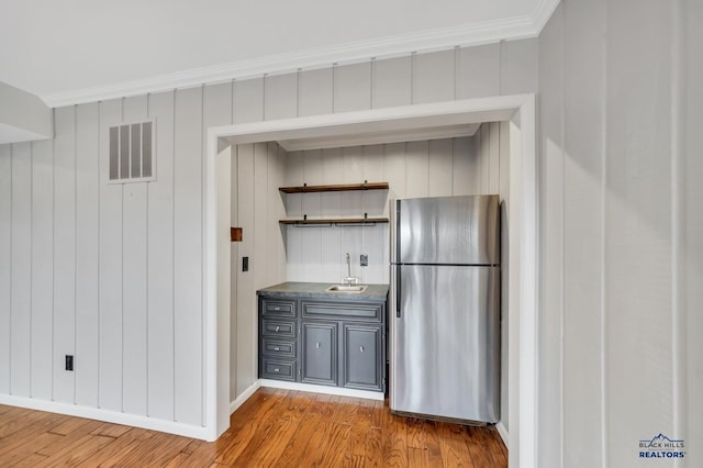 kitchen featuring gray cabinetry, sink, light hardwood / wood-style flooring, ornamental molding, and stainless steel refrigerator