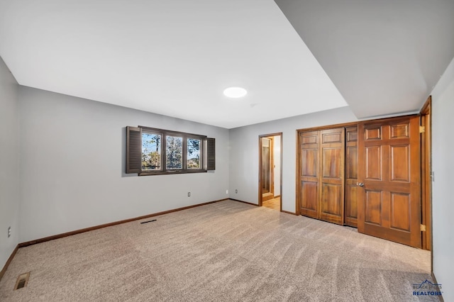 unfurnished bedroom featuring light carpet and a closet